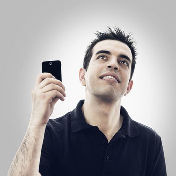 Happy young man with smartphone looks up against white background with copyspace