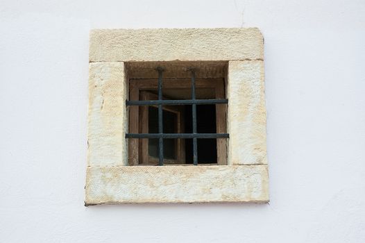 Old open window on white shabby wall with bars