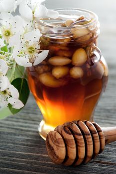 Honey in a jar with different nuts on a dark wooden table