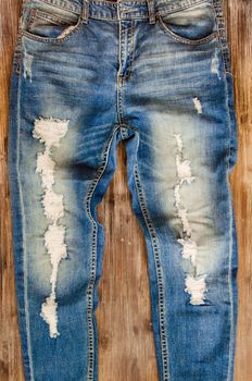 Detail of nice vintage weathered jeans on wood texture