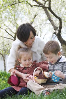 Happy mother and two children in blooming garden with Easter decor elements