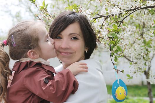 Happy mother and daughter hugging among spring garden