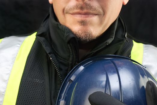 Close-up of a construction worker holding his hardhat to his chest.