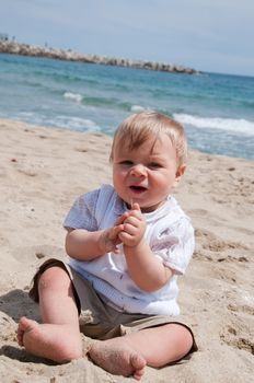 Happy cute little boy sitting on the beach