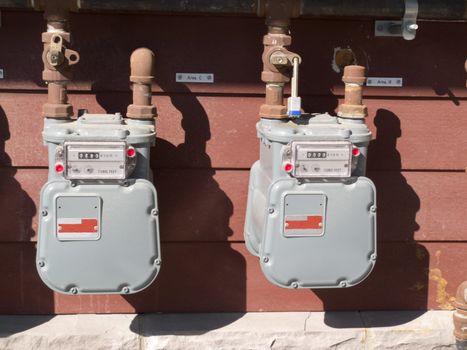 Two residential natural gas meters on exterior wall to measure household energy consumption