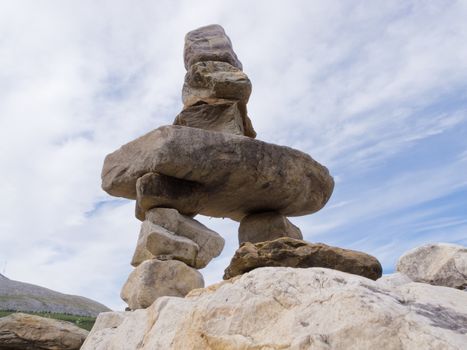 Large rocks stacked and balanced to form an Inuksuk stone landmark or cairn as a marker or monument in mountainous wilderness terrain