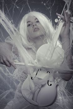 Vogue beautiful woman trapped in a spider web with a white violin, lace dress