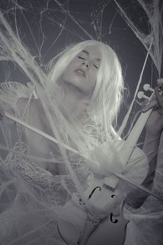 Style beautiful woman trapped in a spider web with a white violin, lace dress