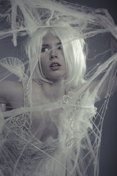 Portrait beautiful woman trapped in a spider web with a white violin, lace dress