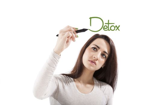 Beautiful healthy girl writing with black marker pen on virtual screen the world detox. Young health professional isolated on white background.