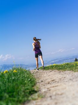 Photo of a young woman jogging and exercising on a country path.  Lake in the distance.