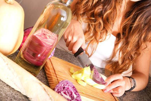 A young woman cutting vegetables ion the kitchen.