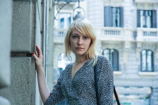 Retro style image of a young adult woman standing in front of a Store in downtown Barcelona, Spain.