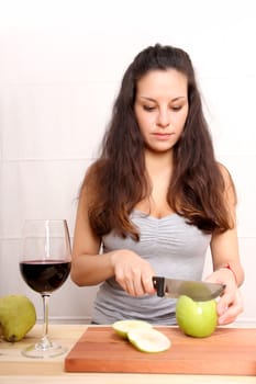 A young adult woman with fruits and wine in the kitchen.