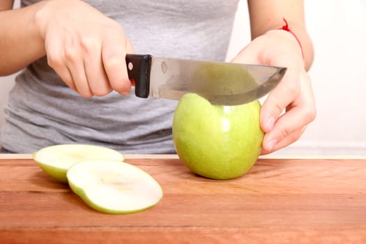 A young adult woman cutting a Apple in the kitchen.