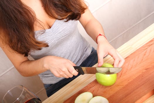 A young adult woman cutting a Apple in the kitchen.