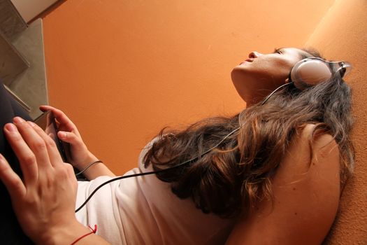 A young woman listening to melancholic Music sitting in the stairway.