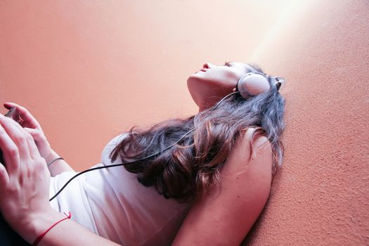 A young woman listening to melancholic Music sitting in the stairway.