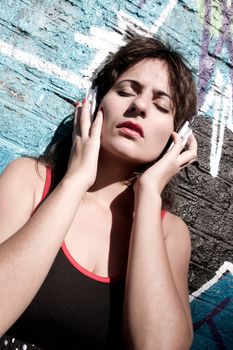 A vintage dressed girl listing to music in a urban environment.