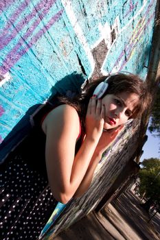 A vintage dressed girl listing to music in a urban environment.