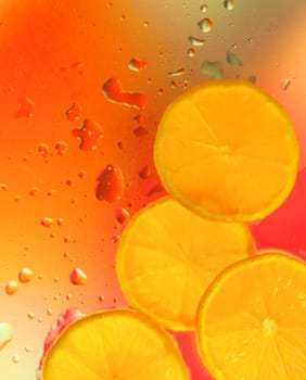 Abstract background. Sections of the orange (mandarin) on glass with water drops