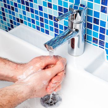 Man washing his hands in a bathroom sink