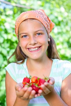 Happy cute girl in summer garden with ripe fresh strawberries.