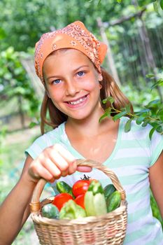 Cute girl with basket of vegetables in summer garden