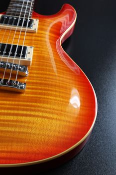 Closeup of electric guitar with cherry sunburst finish and flame maple top.