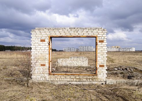 Unfinished garage gate on city outskirts background, cloudy spring day