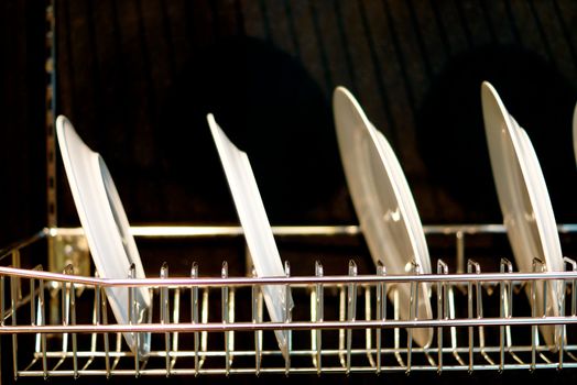 white ceramic dish hang on stainless shelf on black scene,shallow focus