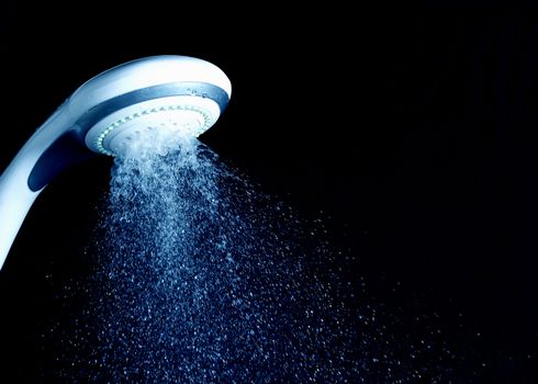 Modern shower head with running water isolated on black background