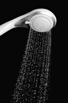 Modern shower head with running water isolated on black background