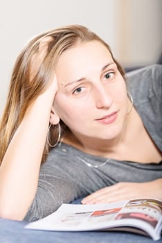 Brunette reading magazine on sofa