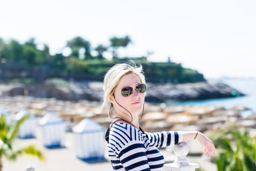 Beautiful young blond woman in aviator sunglasses backlit by sunshine