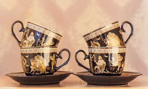 The beautiful tea cups decorated with a list with gold with the image of scenes from antique life.