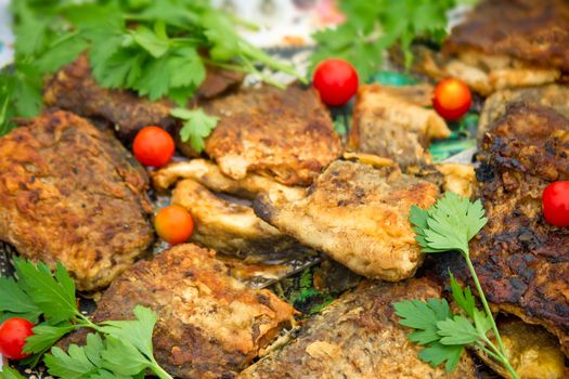 Fried together with spices slices the chickens decorated with leaves of parsley and small tomatoes.
