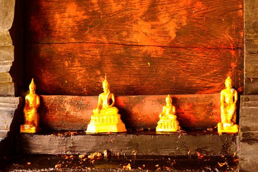 four of gold buddha images on old wood shelf,shallow focus