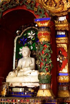 the buddha image that made from white jade and the detail of ancient thai decorated pattern that include handcraft wood carving work,gold painting and decorated with gold plate,mirror and precious stone,Lampang temple,Thailand