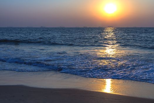 Scenic view from sand beach in Goa to beautiful sunset above the Arabian sea. Sun reflection on sea surface