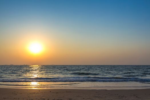 Scenic view from sand beach in Goa to beautiful sunset above the Arabian sea. Sun reflection on sea surface