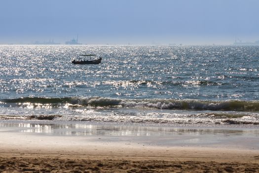 Boats at Arabian sea. Cargo ships on the background. View from beach in Goa, India