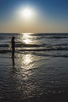 Scenic view from beach in Goa to beautiful sunrise above the Arabian sea. Silhouette of woman or girl looks at sea