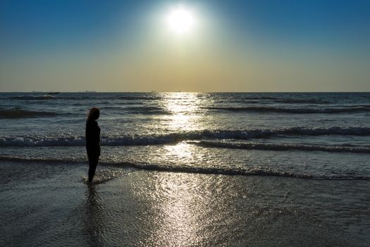 Scenic view from beach in Goa to beautiful sunrise above the Arabian sea. Silhouette of woman or girl looks at sea