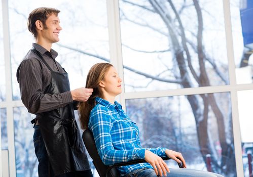 male hairdresser puts woman's hair in a hairdressing salon
