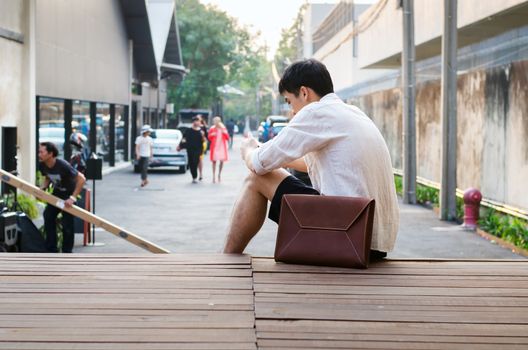 Asian man with leather bag on wooden deck