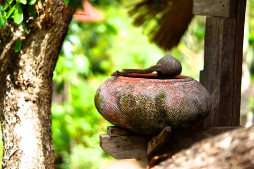 old earthen water containing pot in thai style garden