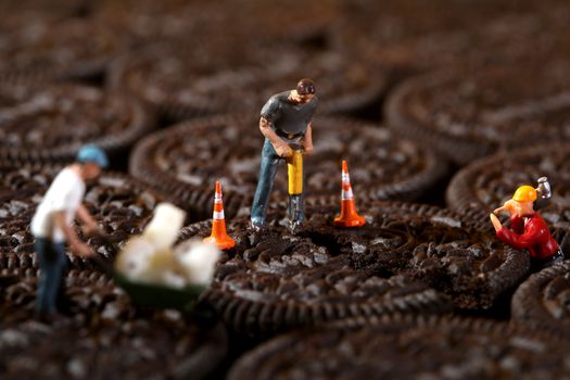 Miniature Construction Workers in Conceptual Imagery With Cookies