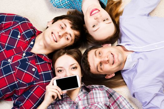 four young men lie together, young attractive woman pressed her lips to the phone