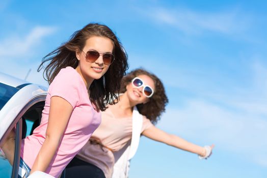 young attractive woman in sunglasses got out of the car window and laugh